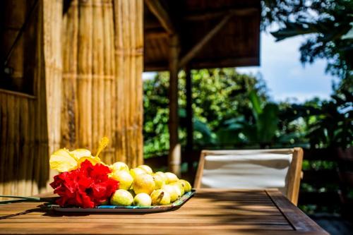 une assiette de fruits sur une table avec un vase de fleurs dans l'établissement Shuit Bambou, à La Trinité