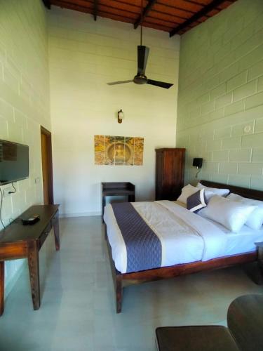 a bedroom with a large bed and a desk and a tv at Coffeeberry Hills Chikamagalur in Chikmagalūr
