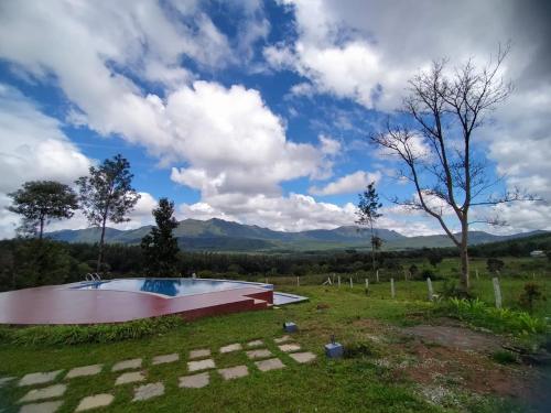 a pool in a field with mountains in the background at Coffeeberry Hills Chikamagalur in Chikmagalūr