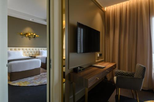 a hotel room with a bed and a desk with a television at The Granite Luxury Hotel Penang in George Town