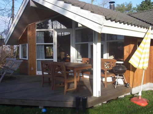 a house with a wooden deck with a table and chairs at Sommerhus i Marielyst med Spa og Sauna, incl el og vand, tæt på by og strand in Marielyst