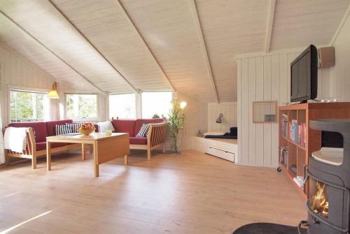 a living room with a couch and a table and a tv at Sommerhus i Marielyst med Spa og Sauna, incl el og vand, tæt på by og strand in Marielyst