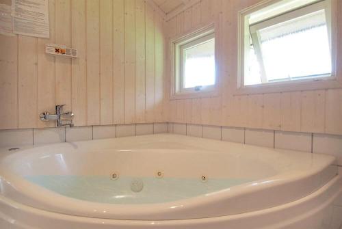 a white bath tub in a bathroom with a window at Sommerhus i Marielyst m/Spa og sauna - tæt på by og strand in Marielyst