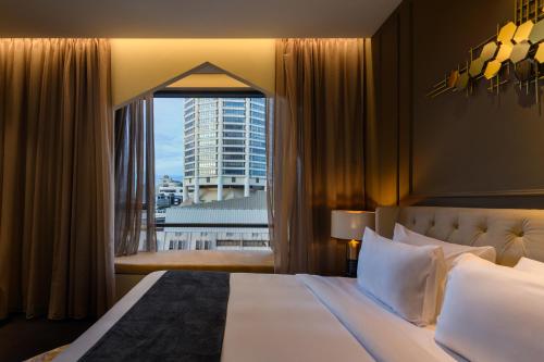 a bedroom with a large bed and a large window at The Granite Luxury Hotel Penang in George Town