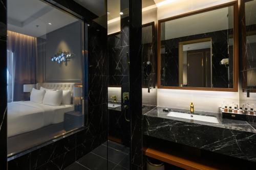 a bathroom with a bed and a sink and a mirror at The Granite Luxury Hotel Penang in George Town