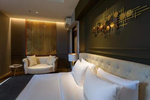 a bedroom with a white bed and a chair at The Granite Luxury Hotel Penang in George Town