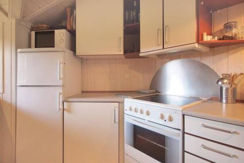 a kitchen with a stove and a white refrigerator at Sommerhus i Marielyst med Spa og Sauna, incl el og vand, tæt på by og strand in Marielyst