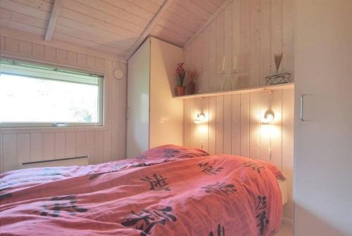 a bedroom with a bed with a pink blanket at Sommerhus i Marielyst m/Spa og sauna - tæt på by og strand in Marielyst