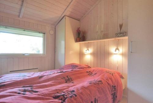 a bedroom with a bed with a pink blanket at Sommerhus i Marielyst med Spa og Sauna, incl el og vand, tæt på by og strand in Marielyst