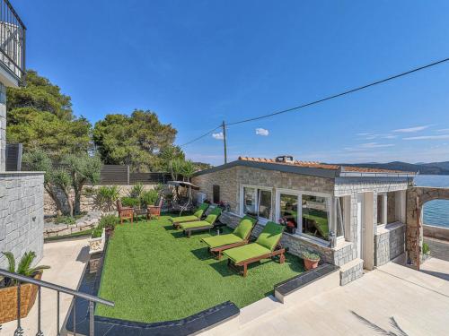 a backyard with green chairs and a house at Villa Pinia in Drvenik Mali