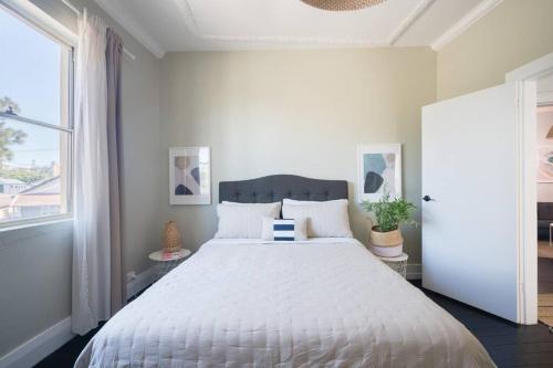 um quarto com uma cama grande e uma colcha branca em Beautiful 2BR Top Floor Bondi Beach Walk to Beach em Sydney