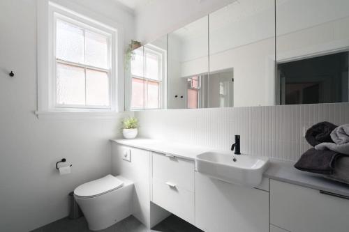 a white bathroom with a sink and a toilet at Beautiful 2BR Top Floor Bondi Beach Walk to Beach in Sydney