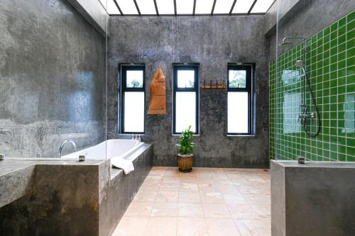 y baño con bañera, lavabo y azulejos verdes. en Cascade Tara en Na Mueang