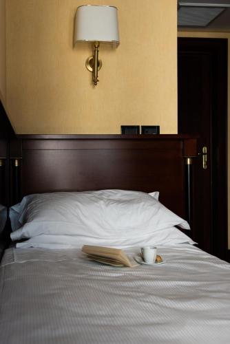 a bed with a book and a cup and a book at Hotel Petite Fleur in Roccaraso