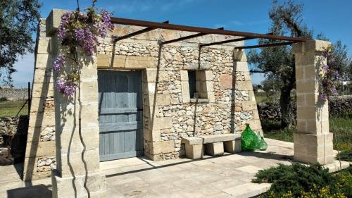 a stone building with a garage with purple flowers at Masseria Ferarelli Trepizzi in Diso