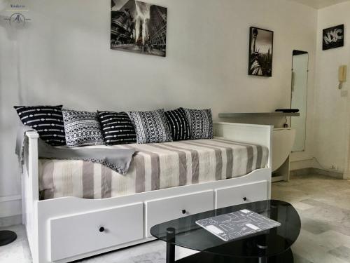 un sofá blanco con almohadas en la sala de estar en LE BROOKLYN - Studio Centre Ville avec climatisation et connexion Wifi, en La Grande-Motte