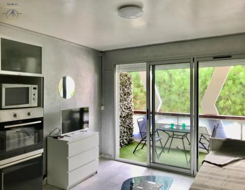 - un salon avec une cuisine et une table avec des chaises dans l'établissement LE BROOKLYN - Studio Centre Ville avec climatisation et connexion Wifi, à La Grande Motte