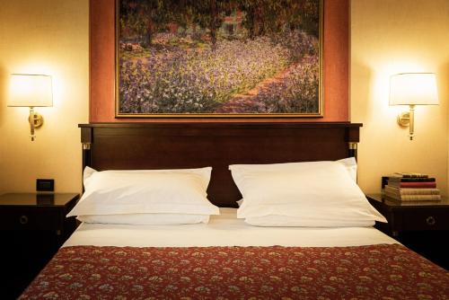 a bedroom with a bed with a painting on the wall at Hotel Petite Fleur in Roccaraso