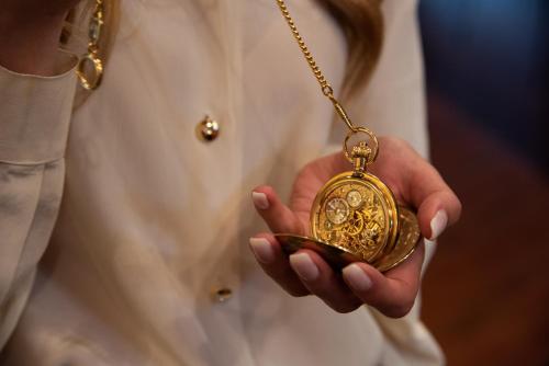 a woman holding a gold pocket watch on a chain at Hotel Petite Fleur in Roccaraso