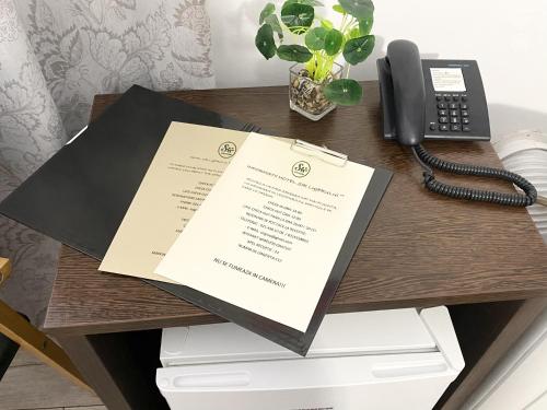 a desk with a phone and papers on it at Hotel Sir Lujerului in Bucharest