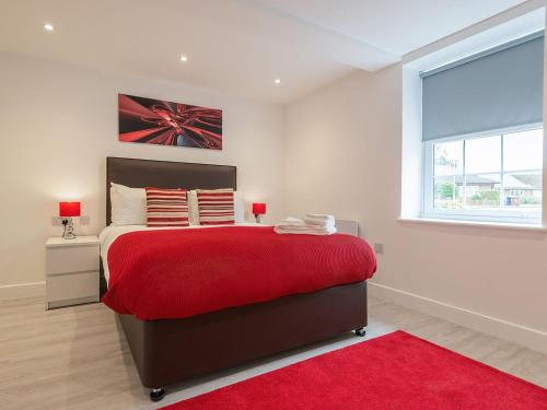 a bedroom with a red bed with a red rug at The Suffolk-uk41441 in Brandon
