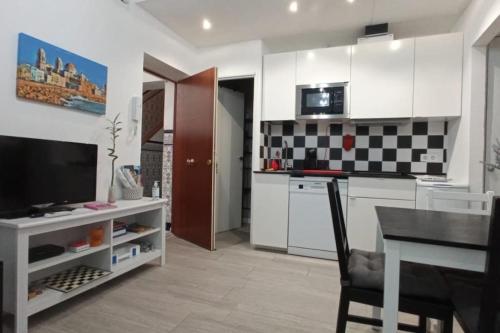 uma cozinha com armários brancos e uma mesa com uma sala de jantar em CDZ - Casa de los Viajeros Pasquín em Cádiz