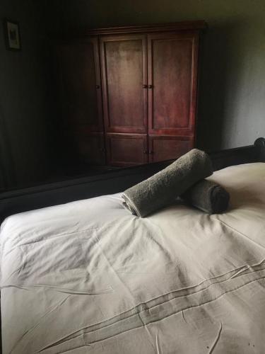 a white bed in a bedroom with a wooden cabinet at Kruger Ranch in Magaliesburg