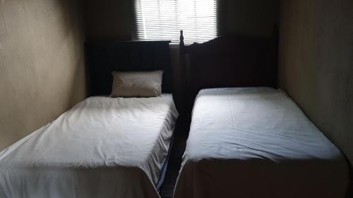 two twin beds in a small room with a window at Kruger Ranch in Magaliesburg