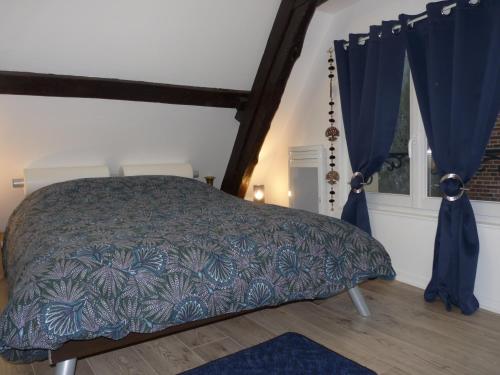 a bedroom with a bed with blue curtains at Gîte d’Eros in Saint-Valery-sur-Somme