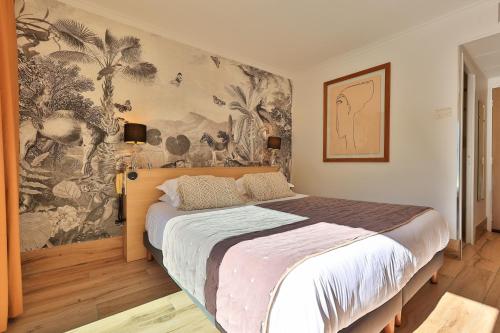 サント・マキシムにあるル プティ プランスのベッドルーム1室(壁に絵画が描かれた大型ベッド1台付)