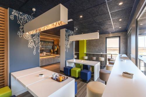 a restaurant with white tables and colorful chairs at ibis budget Lyon Gerland in Lyon