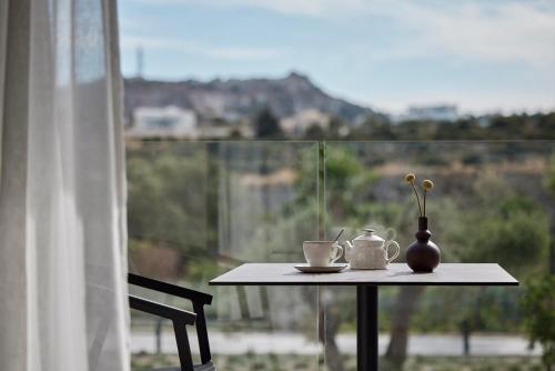 a table with a coffee cup and a vase on a balcony at Helea Lifestyle Beach Resort in Kallithea Rhodes