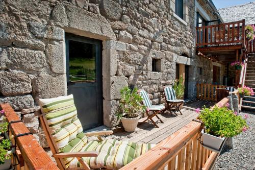 a patio with rocking chairs and a stone building at Logis Les Granges de Bigose in Rimeize