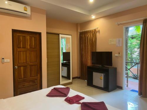 a bedroom with a bed and a television and a door at Ao Thong beach Resort in Khao Lak