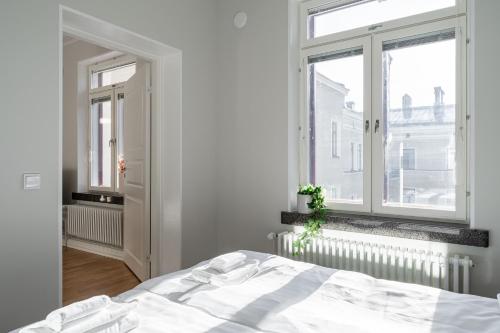 a white bedroom with a bed and a window at 2ndhomes Tampere Luxurious "Keskustori" Apartment - Private Sauna & Great Location in a Historical Building in Tampere