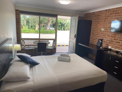 a bedroom with a bed and a desk and a window at Lake Macquarie Motor Inn in Belmont