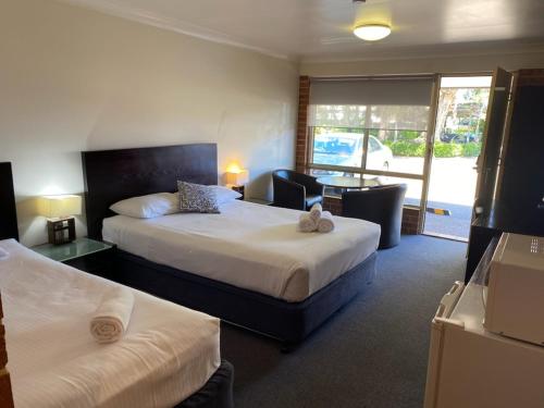 a hotel room with two beds and a balcony at Lake Macquarie Motor Inn in Belmont