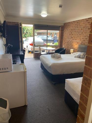 a hotel room with two beds and a table and chairs at Lake Macquarie Motor Inn in Belmont