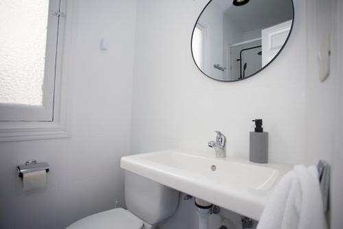 ein weißes Badezimmer mit einem Waschbecken und einem Spiegel in der Unterkunft Gran Via Experience in Madrid