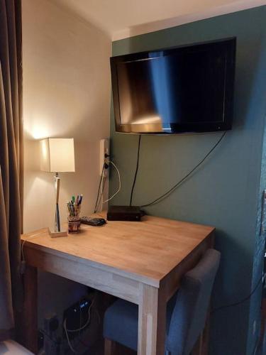 a wooden table with a television on a wall at Le Reposoir Maison spacieuse avec feu au bois in Bertogne