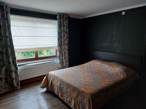 een slaapkamer met een bed naast een raam bij Le Reposoir Maison spacieuse avec feu au bois in Bertogne