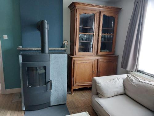 a living room with a stove and a couch at Le Reposoir Maison spacieuse avec feu au bois in Bertogne