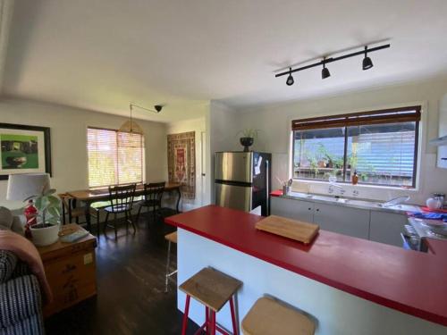 cocina y sala de estar con encimera roja en The Cabin at Lake Tyers, en Lake Tyers
