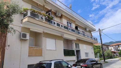 budynek z dwoma samochodami zaparkowanymi przed nim w obiekcie Apartment Marina 3 w mieście Asprovalta