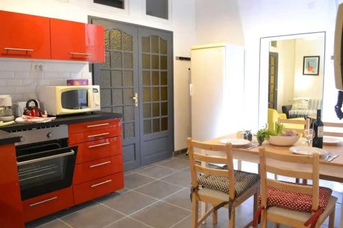 une cuisine avec des placards rouges et une table avec un four micro-ondes dans l'établissement Comédie Beau T3 Climatisé Cosy avec 2 Suites, à Montpellier