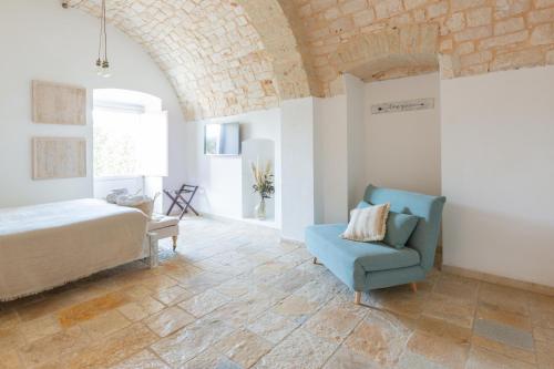 a bedroom with a bed and a blue chair at Tenuta Pinto in Mola di Bari