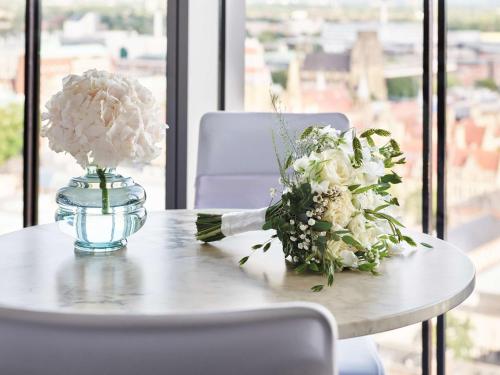 a table with a vase and flowers on it at Hyatt Regency Manchester in Manchester