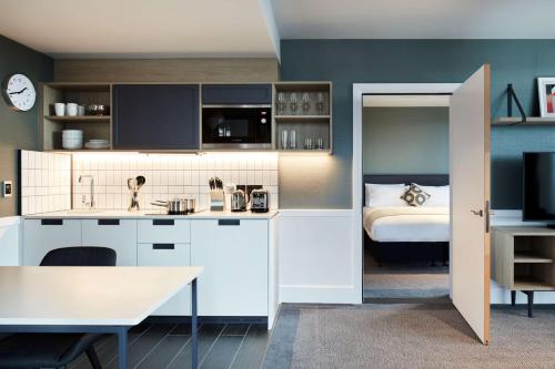 a kitchen with white cabinets and a bed in a room at Hyatt House Manchester - Aparthotel in Manchester