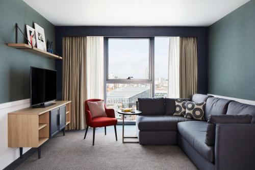 a living room with a couch and a television at Hyatt House Manchester - Aparthotel in Manchester