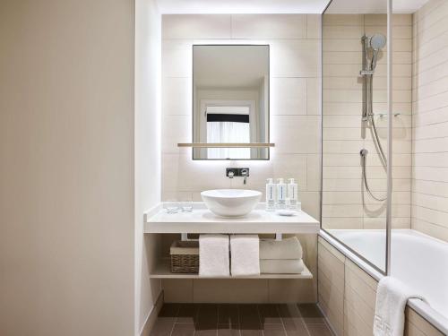 a bathroom with a sink and a shower and a tub at Hyatt House Manchester - Aparthotel in Manchester